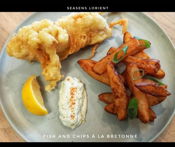 Délicieux poisson frit avec frites bretonnes, accompagnés d'une sauce maison et d'un quartier de citron, parfait pour une expérience culinaire authentique.