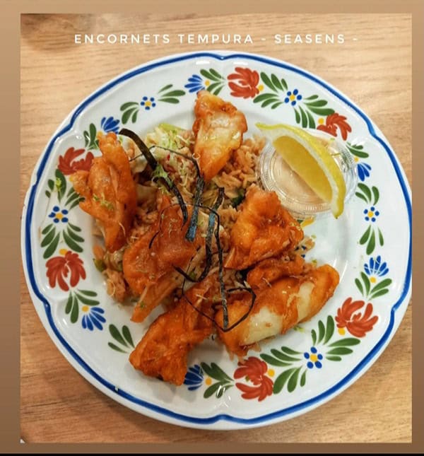 Plat de fruits de mer avec coquillages, crustacés, et citron, présenté sur une assiette décorative colorée, prêt à déguster.